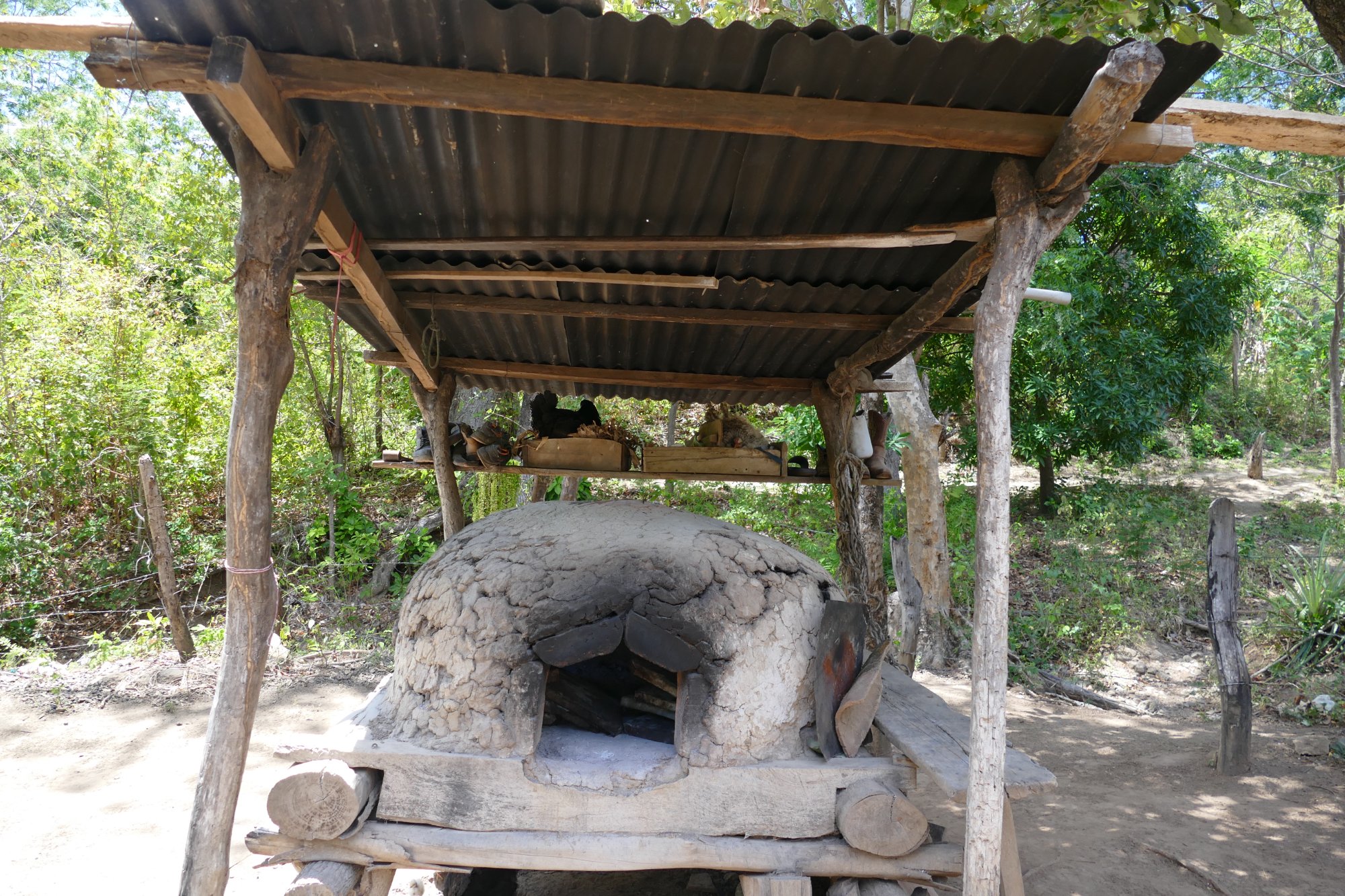 A traditional clay outdoor oven beneath a wooden shelter on Marcia's farm